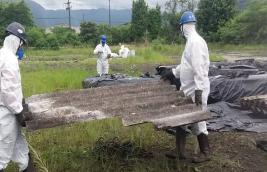 Equipe com trajes de proteção na remoção de telhas de fibrocimento em área contaminada