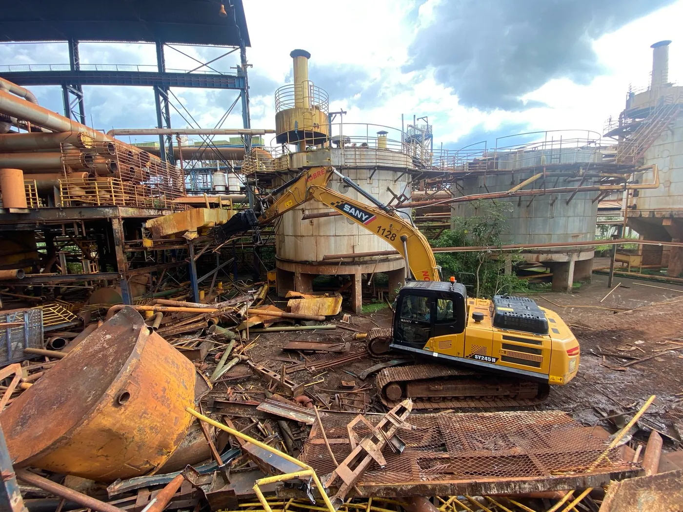 Escavadeira no desmonte de tanques e tubulações em planta industrial